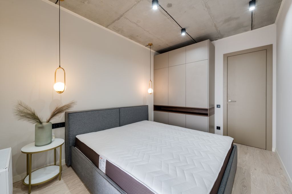 A minimalist bedroom featuring a gray bed, warm lighting, and sleek storage solutions.