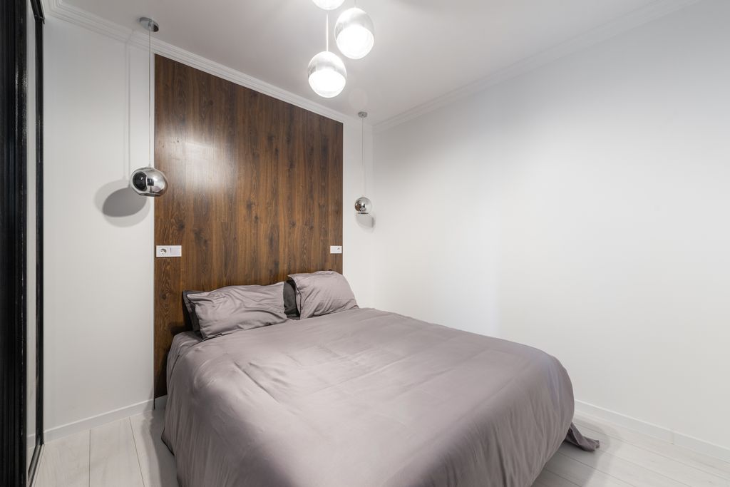 Contemporary bedroom with sleek design, wooden accents, and pendant lights.
